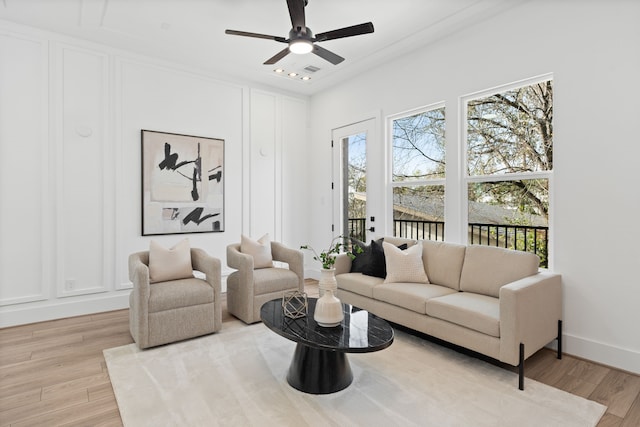 living area with a ceiling fan, plenty of natural light, and light wood-style flooring