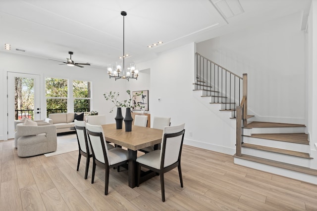 dining area featuring stairway, baseboards, ceiling fan with notable chandelier, and light wood finished floors