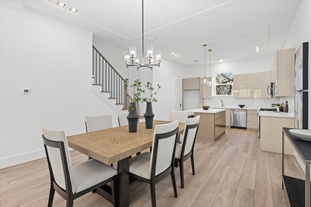 dining space with an inviting chandelier, light wood finished floors, and stairs