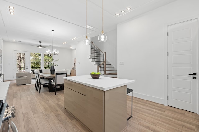 kitchen with a kitchen island, range, light wood-type flooring, ceiling fan with notable chandelier, and open floor plan