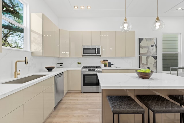 kitchen featuring a sink, appliances with stainless steel finishes, modern cabinets, and light wood-style flooring