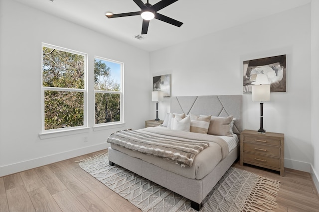 bedroom featuring baseboards, ceiling fan, wood finished floors, and visible vents
