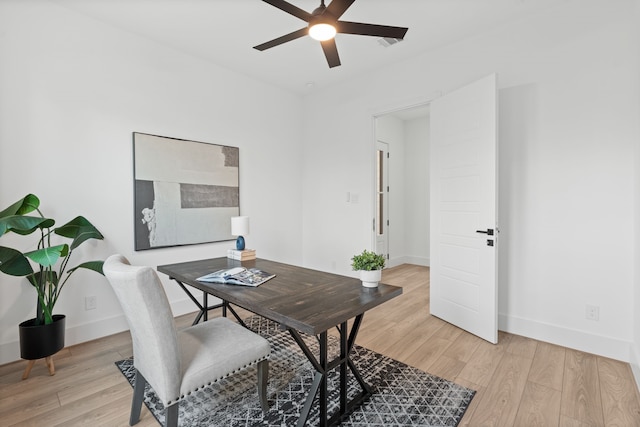 office space featuring a ceiling fan, baseboards, and light wood-type flooring
