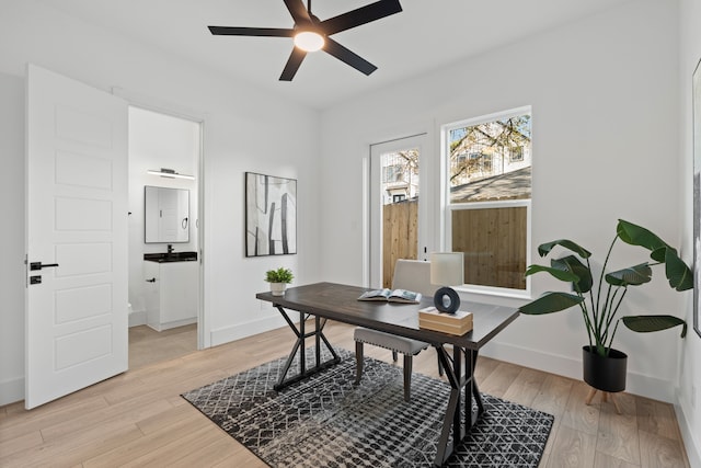 home office with baseboards, a ceiling fan, and light wood-style flooring