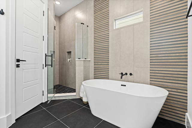 full bath featuring tile patterned floors, a soaking tub, tile walls, and a shower stall