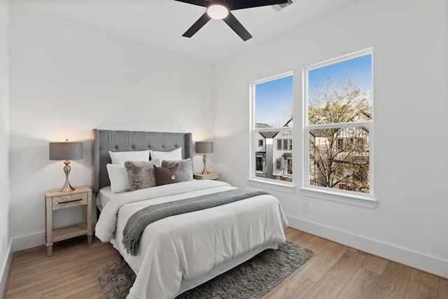 bedroom featuring a ceiling fan, baseboards, and light wood-style floors