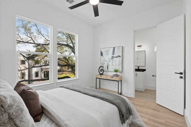 bedroom with connected bathroom, a ceiling fan, visible vents, and light wood-type flooring