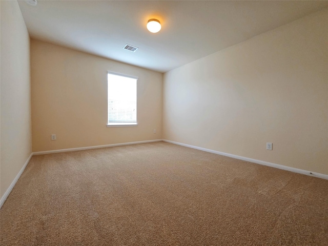 spare room featuring baseboards, visible vents, and light carpet