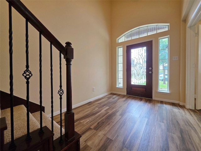 entrance foyer featuring baseboards, a wealth of natural light, stairway, and wood finished floors