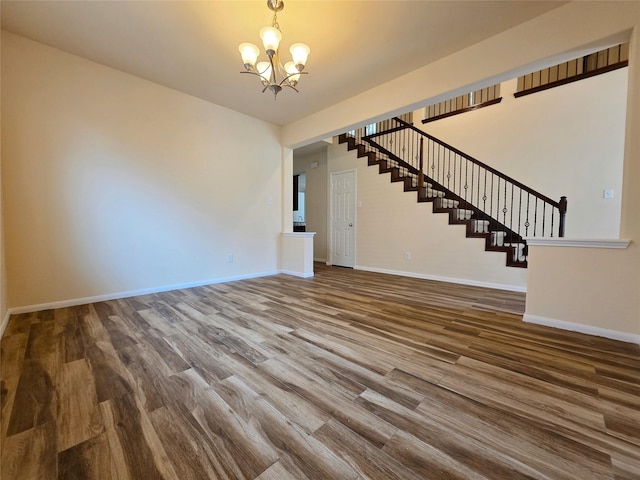 interior space with stairs, baseboards, an inviting chandelier, and wood finished floors
