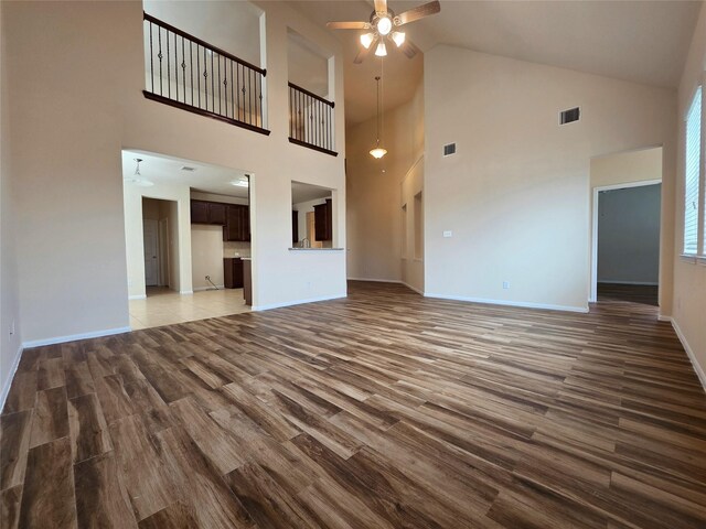 unfurnished living room with a ceiling fan, high vaulted ceiling, visible vents, and wood finished floors