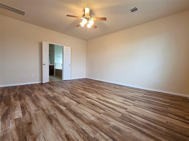 empty room featuring a ceiling fan, baseboards, visible vents, and wood finished floors