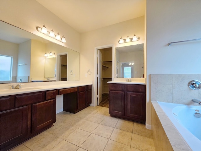 bathroom featuring a walk in closet, a sink, tile patterned flooring, two vanities, and a bath