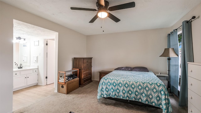bedroom featuring a sink, ensuite bathroom, light carpet, and ceiling fan