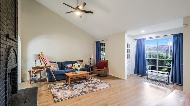 living area featuring a brick fireplace, baseboards, ceiling fan, high vaulted ceiling, and light wood finished floors