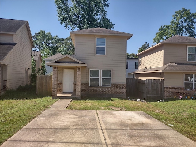 traditional home featuring brick siding, fence, and a front lawn