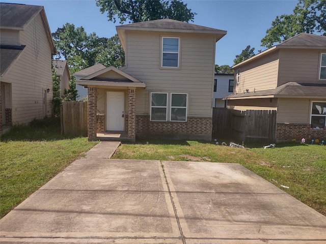 traditional-style house with brick siding, fence, and a front yard
