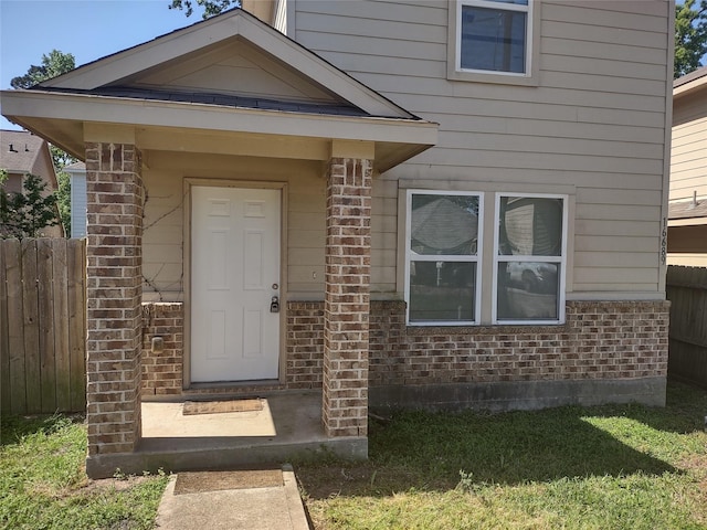 entrance to property featuring brick siding and fence