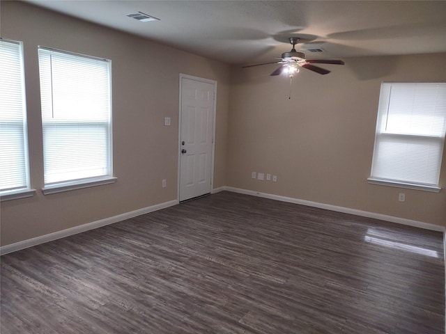 empty room featuring baseboards, visible vents, a ceiling fan, and dark wood-type flooring
