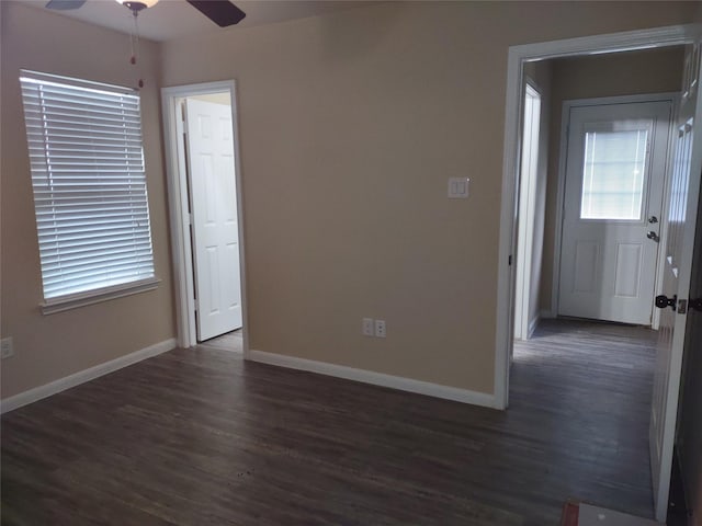 empty room featuring baseboards, a ceiling fan, and dark wood-style flooring