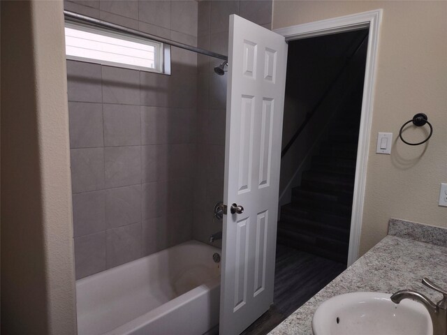 bathroom with wood finished floors, a sink, and shower / bathtub combination