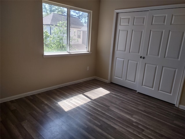 unfurnished bedroom featuring baseboards, dark wood-style floors, and multiple windows