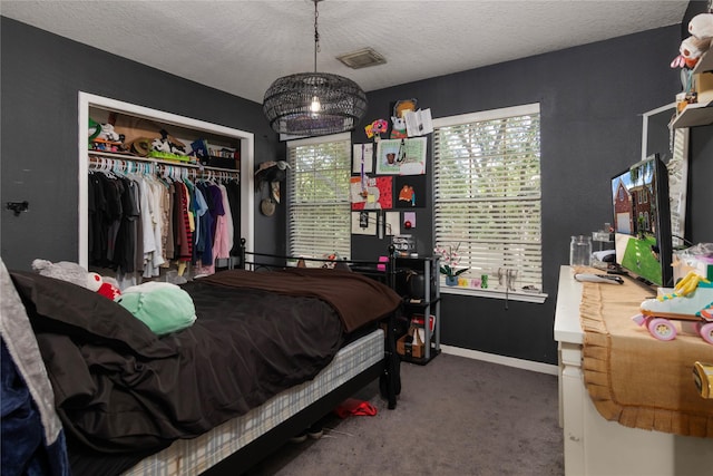 bedroom featuring a closet, a textured ceiling, visible vents, carpet flooring, and baseboards