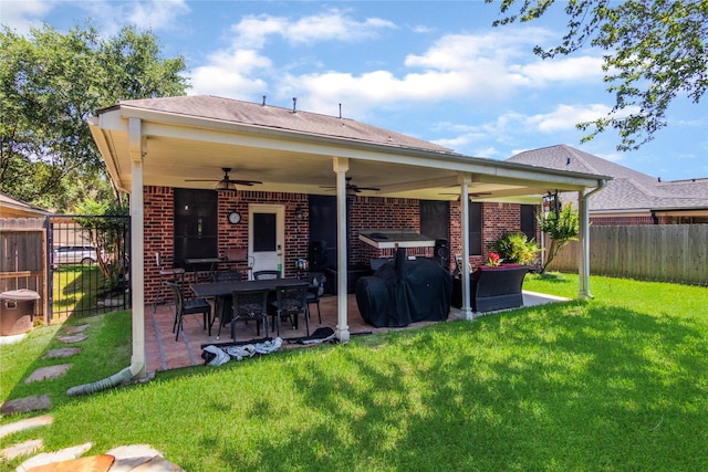 rear view of property with a ceiling fan, a lawn, brick siding, a patio area, and a fenced backyard