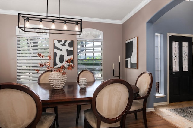 dining area with baseboards, ornamental molding, arched walkways, and wood finished floors