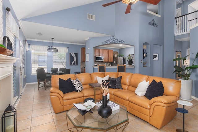 living area featuring light tile patterned floors, visible vents, baseboards, and ceiling fan