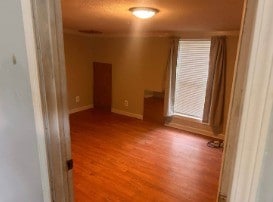 spare room with baseboards and wood finished floors
