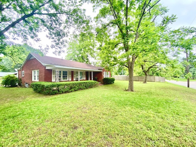 view of front facade with brick siding, a front lawn, and fence