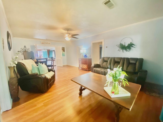 living area with a ceiling fan, light wood finished floors, and visible vents