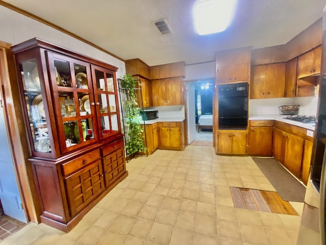 kitchen with visible vents, light floors, light countertops, a warming drawer, and black appliances
