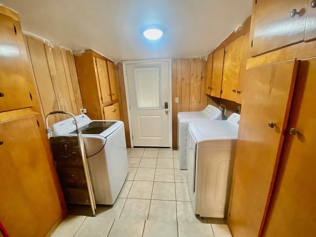 clothes washing area with cabinet space, light tile patterned flooring, and washer and dryer