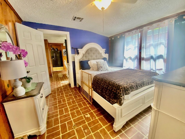 bedroom featuring visible vents, a textured ceiling, brick floor, and ceiling fan