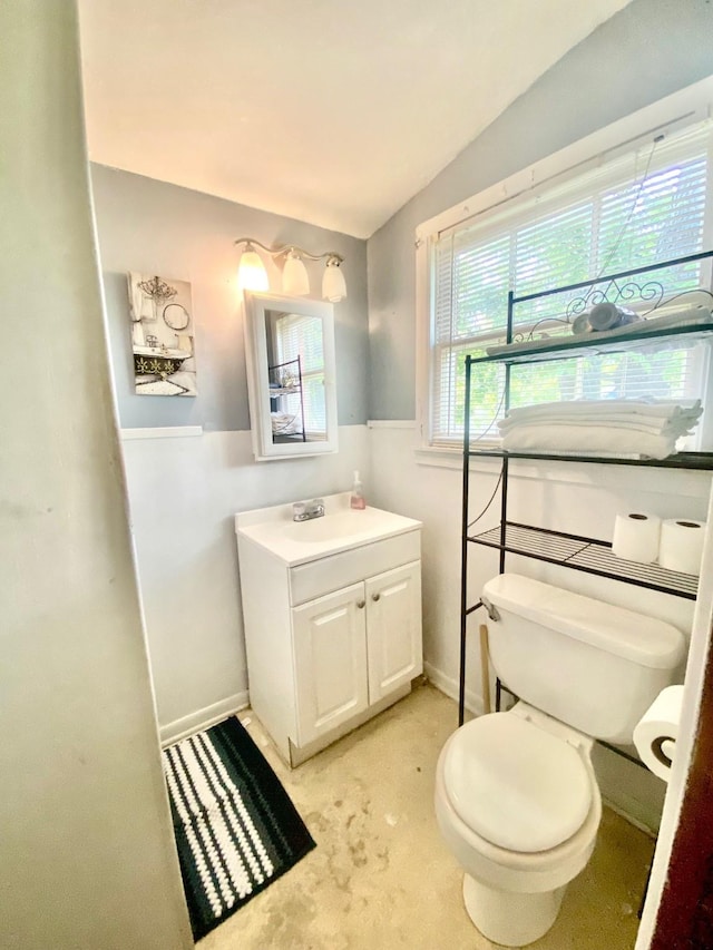 bathroom featuring toilet, baseboards, lofted ceiling, and vanity