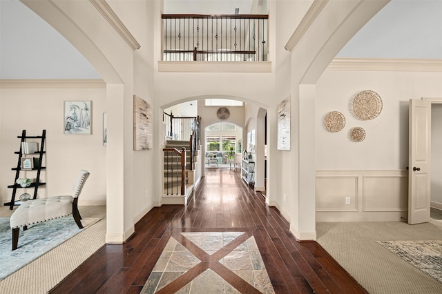 foyer entrance featuring arched walkways, hardwood / wood-style floors, and ornamental molding