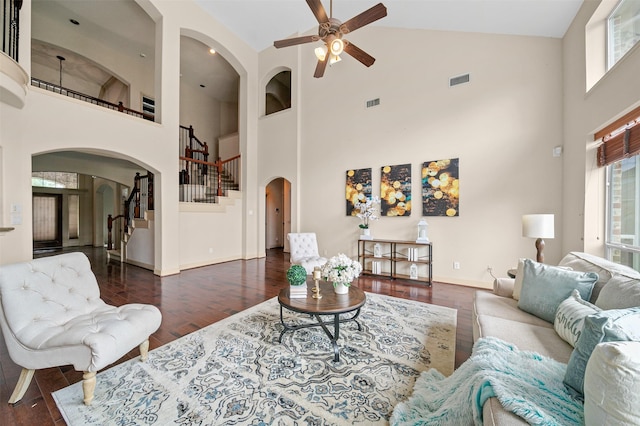 living room with stairway, arched walkways, high vaulted ceiling, and a wealth of natural light