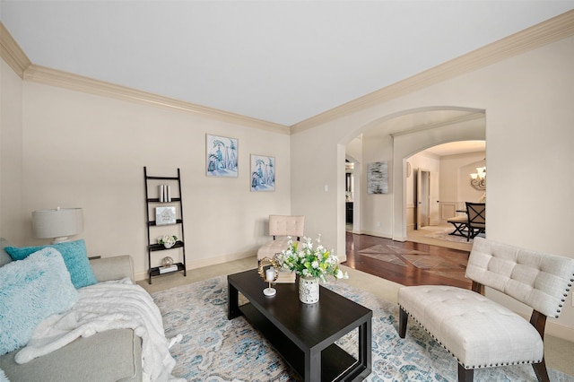 living room featuring an inviting chandelier, arched walkways, baseboards, and ornamental molding