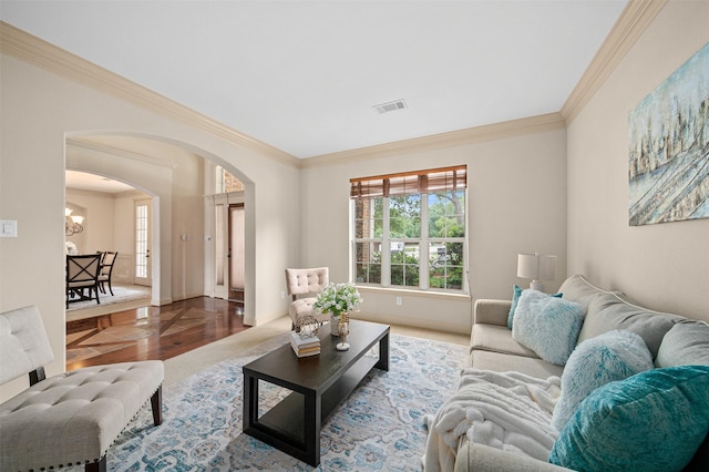 living area with crown molding, visible vents, an inviting chandelier, wood finished floors, and arched walkways