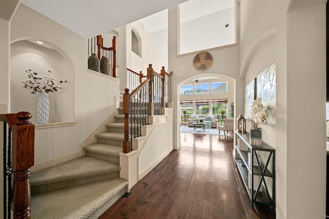 entryway with stairway, baseboards, a high ceiling, and dark wood-style floors