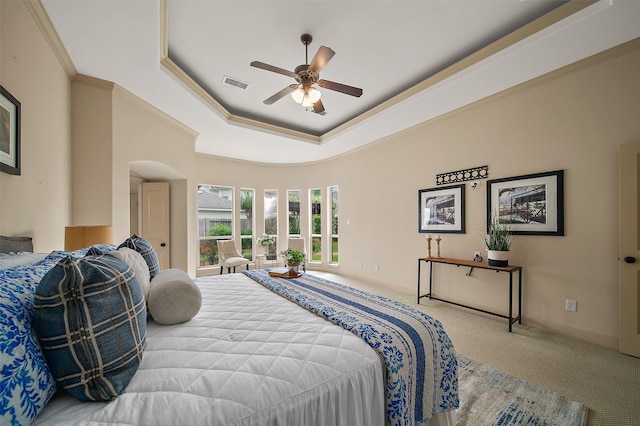 carpeted bedroom with crown molding, arched walkways, baseboards, a tray ceiling, and visible vents