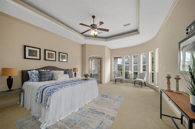 bedroom with a tray ceiling, arched walkways, light colored carpet, and visible vents