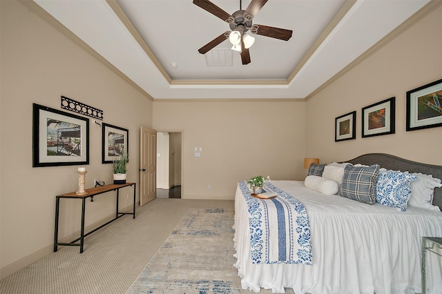bedroom featuring ceiling fan, ornamental molding, a tray ceiling, and light colored carpet