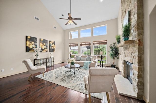 living room featuring visible vents, hardwood / wood-style floors, a stone fireplace, ceiling fan, and high vaulted ceiling