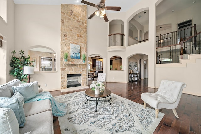 living area featuring ceiling fan, wood-type flooring, and a towering ceiling