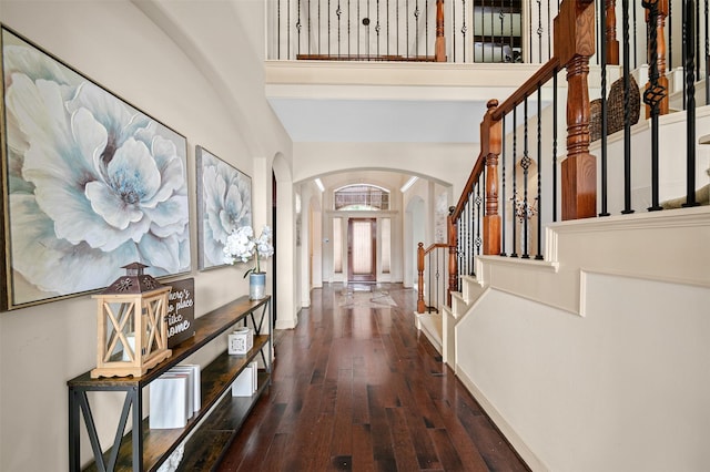 foyer with arched walkways, stairway, and hardwood / wood-style floors
