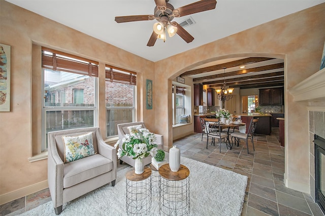 interior space featuring baseboards, arched walkways, ceiling fan with notable chandelier, and stone tile flooring
