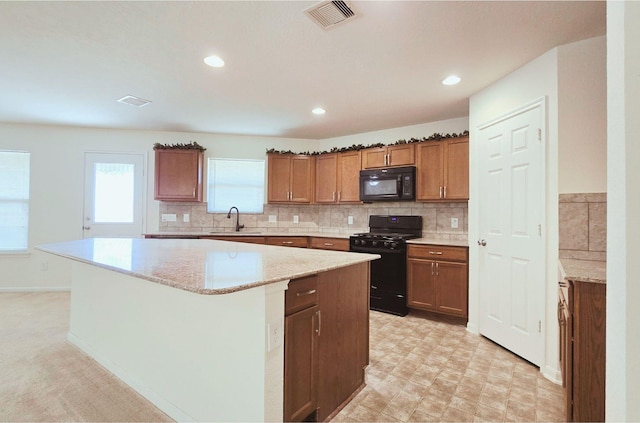 2702 Urban Glen Ct, Houston, TX 77038 - kitchen with black appliances, a center island, a sink, brown cabinetry, and backsplash